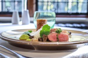 un plato de comida con carne y un vaso de agua en Langshott Manor - Luxury Hotel Gatwick en Horley