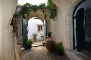 an alley with an archway with plants and a large vase at Axion Studios in Aroniadika
