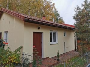 a small white house with a red door at WHITE Apartment in Jabłonna