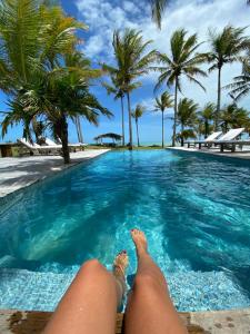 a person laying in a swimming pool with palm trees at Vila Bela Vista in Corumbau
