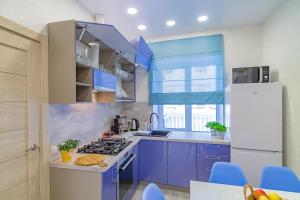 a kitchen with blue cabinets and a white refrigerator at БЕСКОНТАКТНОЕ ЗАСЕЛЕНИЕ - GoldenRingApartments Super Central Location in Yaroslavl