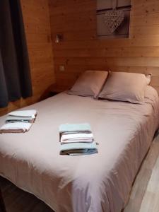 Saint-GenièsにあるLe chalet douilletのベッドルーム1室(白いベッド1台、タオル付)