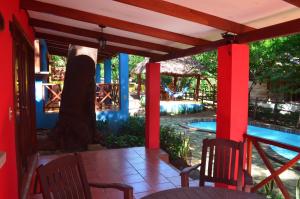 a patio with two chairs and a tree next to a pool at Los Volcanes, Playa el Coco in Escameca