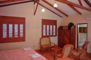 a bedroom with a bed and chairs and windows at Los Volcanes, Playa el Coco in Escameca
