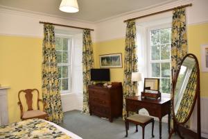 a bedroom with a bed and a desk and a mirror at Applegarth House in Lockerbie
