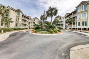 a street in front of a building with palm trees at Port O'Call C-201 in Isle of Palms