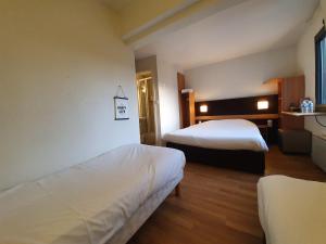 a hotel room with two beds and a table at Hôtel Inn Design & Restaurant Chartres in Chartres +24 photos