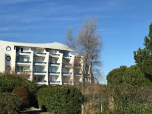 un edificio bianco con alberi di fronte di Appartement classé, vue mer, clim, wifi, parking a La Grande-Motte