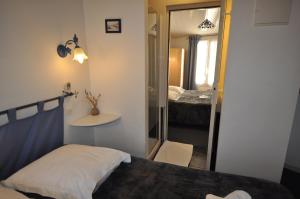 a small bedroom with a bed and a mirror at Le Concept Hotel in Les Portes