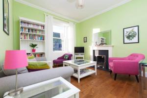 a living room with a couch and pink chairs at Bright and Modern Causewayside Apartment in Edinburgh