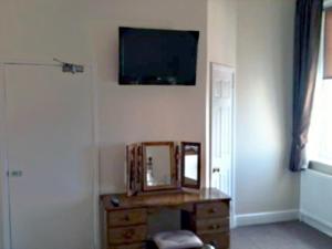 a room with a mirror and a tv on the wall at Clifton Hotel in Weymouth