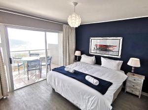 a bedroom with a bed and a balcony with a table at Cape Town Beachfront Accommodation in Blouberg in Bloubergstrand