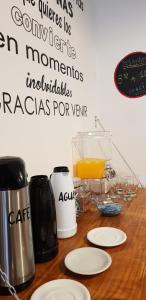 una mesa con platos blancos y un vaso de zumo de naranja en Hostería Barca en Villa Gesell