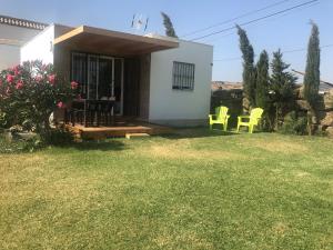 a small white house with yellow chairs in the yard at La Casita de Laura in Bolonia