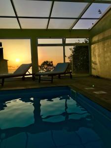 a swimming pool with a view of the sunset at Casa da Relva com Piscina Aquecida Interna in Arco da Calheta
