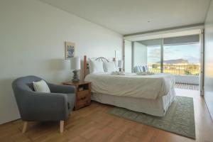 a bedroom with a bed and a chair and a window at Quinta do Mar in Angra do Heroísmo