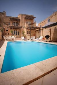 a large blue swimming pool in front of a building at Gozo Break Farmhouses in Kerċem