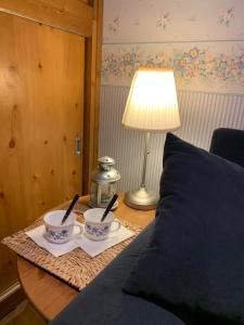 a table with two cups and a lamp on a bed at Casa Vacanza Roccaraso in Roccaraso