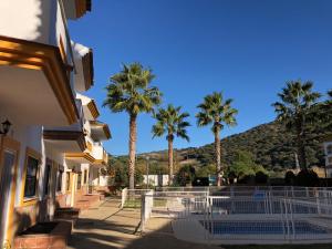 un edificio con palmeras y una montaña en el fondo en Casa Rural las Rosas de Benaojan, en Benaoján