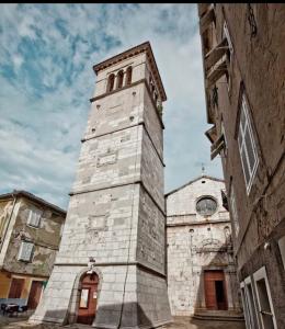 a tall stone clock tower next to a building at Apartment Brđanović in Cres