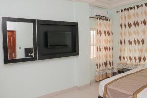 a bedroom with a flat screen tv on a wall at BERACA INN in Cotonou