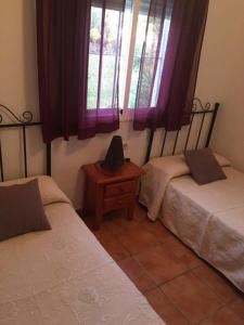 a bedroom with two beds and a window with purple curtains at Casa en Bolonia muy cerca de la playa in Bolonia