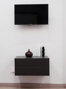 a black dresser with a television on a white wall at Plebiscito Home Holidays in Naples