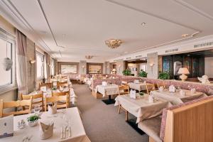 un comedor con mesas y sillas blancas en Hotel Enzian en Zürs am Arlberg