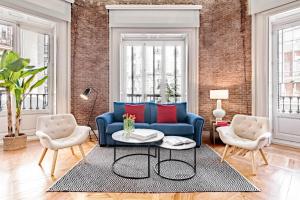 sala de estar con sofá azul y 2 sillas en Sagasta Suites Luxury Apartments, en Madrid