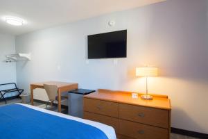 Habitación de hotel con cama, escritorio y TV. en Americas Best Value Inn East Peoria, en Peoria