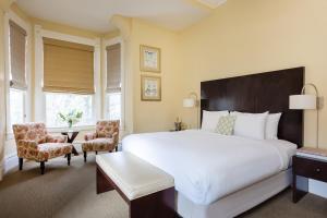 a bedroom with a large white bed and two chairs at Healdsburg Inn on the Plaza, A Four Sisters Inn in Healdsburg