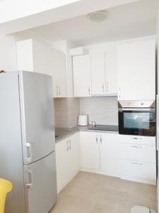 eine weiße Küche mit weißen Schränken und einem Kühlschrank in der Unterkunft Dimitra apartman in Šabac