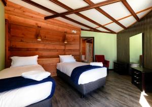 two beds in a room with wooden walls at Taylors Bay Cottage in South Bruny