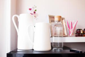 three white vases and a glass bottle on a shelf at The Rosewood Torquay in Torquay