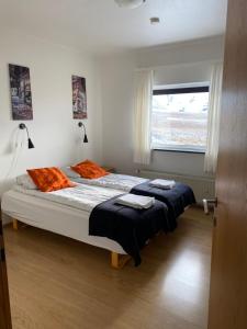 a bedroom with two beds with orange pillows and a window at Kirkjufell Guesthouse and Apartments in Grundarfjordur