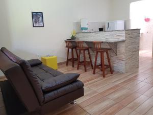 sala de estar con sofá y bar con taburetes en Pousada Refúgio Ninho Verde Jacone Saquarema, en Saquarema