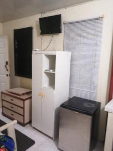 um quarto com um armário branco e uma televisão na parede em Tonys Guest House em Port of Spain