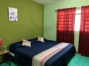 um quarto com uma cama e cortinas vermelhas em casa alegria em Mérida