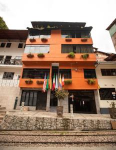 an orange building with flags in front of it at Nativus Hostel Machu Picchu in Machu Picchu