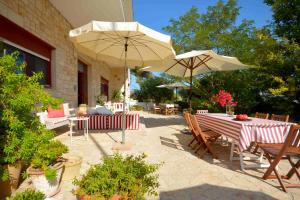een patio met tafels, stoelen en parasols bij fuoridalgusciohome in Leuca