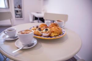 a table with a plate of pastries and cups of coffee at AllYouCanTrip - La Nova in Naples