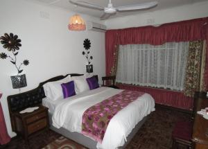 a bedroom with a large bed with purple pillows at Parrot Lodge in Bulawayo