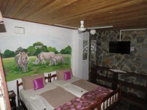 a room with two beds and a painting on the wall at Parrot Lodge in Bulawayo