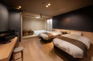 a bedroom with two beds and a flat screen tv at Connect inn Shichijo-Kamogawa in Kyoto