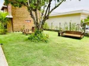 a yard with two benches and a tree at CHALES VILLAGE COR-PENINSULA DE MARAU-BAHIA in Barra Grande