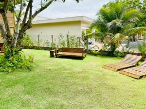 a yard with two benches and a house at CHALES VILLAGE COR-PENINSULA DE MARAU-BAHIA in Barra Grande