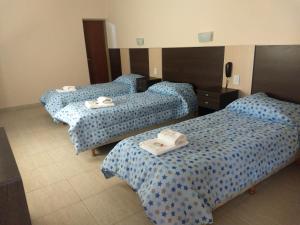 Tres camas en una habitación de hotel con toallas. en hotel andino en La Rioja