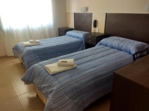 Dos camas en una habitación de hotel con toallas. en hotel andino en La Rioja