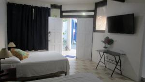 Un dormitorio con dos camas y un televisor de pantalla plana. en Sueño Tranquilo, en Quepos