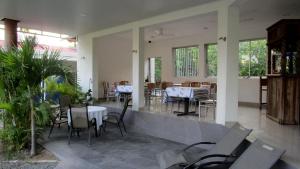 a dining room with chairs and tables and windows at Sueño Tranquilo in Quepos
